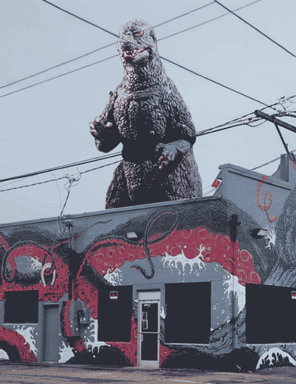 Godzilla towering over the DECAY building and its octopus mural